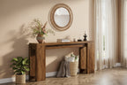 A rustic wooden console table styled in a warm, neutral-toned room with a round woven mirror, potted plant, and curtains.